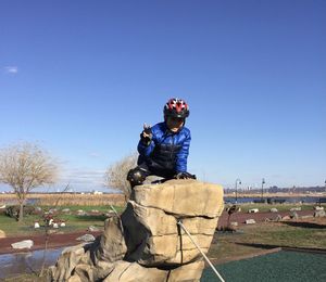 Happy boy on rock against blue sky