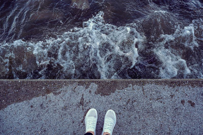 Low section of person standing by water