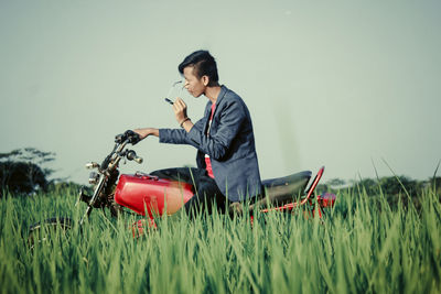 Side view of man holding sunglasses on field