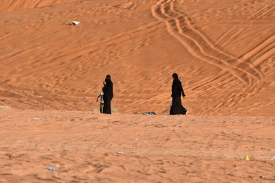 People walking on sand dune in desert