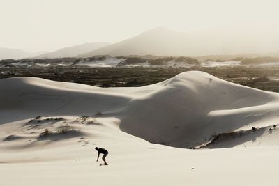 Man practicing sandboard in sand dunes in sunny day