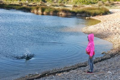 Side view of girl skimming stones in lake