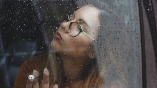 Portrait of woman in wet glass window