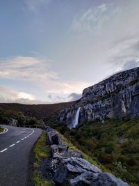 Road leading towards mountain against sky