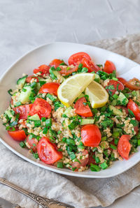 Tabbouleh salad on a dish on light gray concrete background. lebanese cuisine.