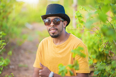 Portrait of young man wearing hat standing against plants