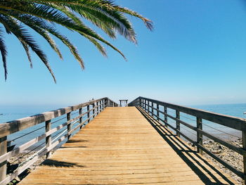 Pier at shore and sea against clear blue sky