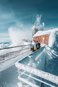 Built structure by sea against snow covered landscape