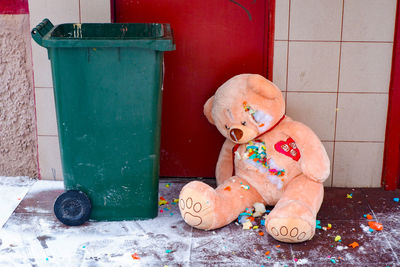 A gutted stuffed teddy bear lies torn apart by a dumpster