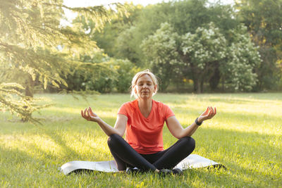 Portrait of young woman using mobile phone while sitting on field