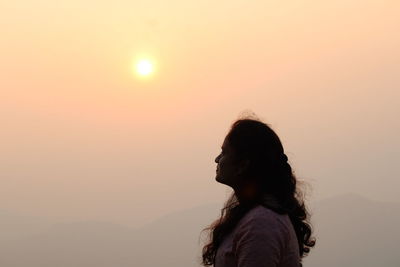 Side view of woman looking away against sky during sunrise a day with a beautiful sunrise