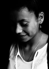 Close-up portrait of young woman against black background