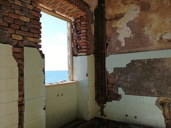 Abandoned building by sea against sky