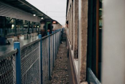 Close-up of railing by railroad tracks in city