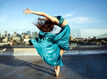 Woman dancing against sky in city