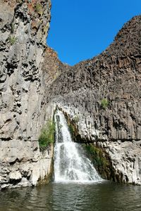 Scenic view of waterfall against sky