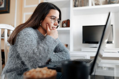 Young woman using phone while sitting on table