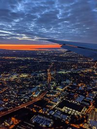 Aerial view of illuminated cityscape against sky during sunset