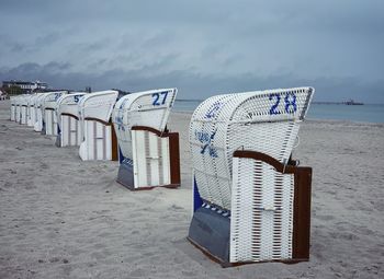 Hooded chairs on beach against sky