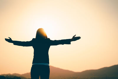 Rear view of silhouette person standing against sky during sunset