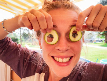 Young woman making a funny joke by using cucumbers as eyeglasses