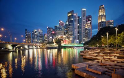 Illuminated buildings by river against sky in city at night