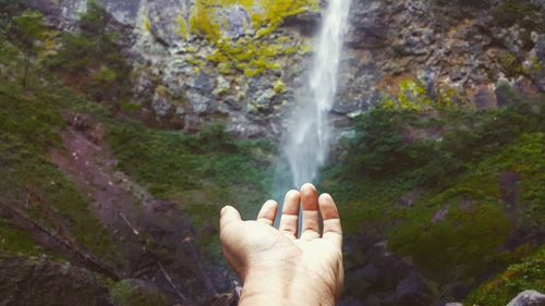 Cropped hand against waterfall