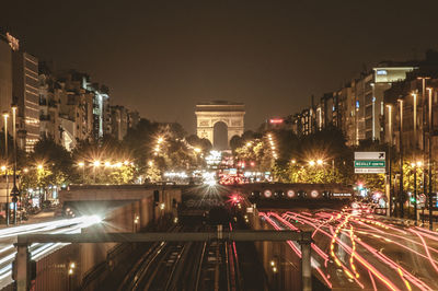 Light trails on road in city with arc de triomphe in background at night