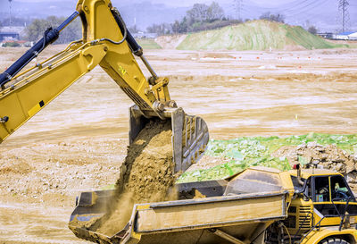 Digger loading a trailer on construction site