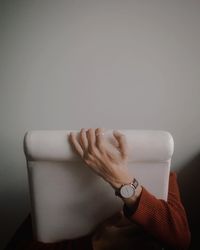 Close-up of woman hand holding sofa against white wall