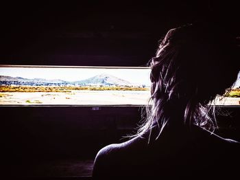 Rear view of woman looking through window