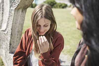 Happy female friends talking while sitting at university campus