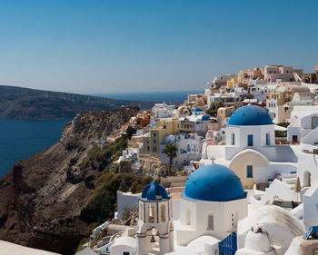 Buildings in greek village coastline against blue sky