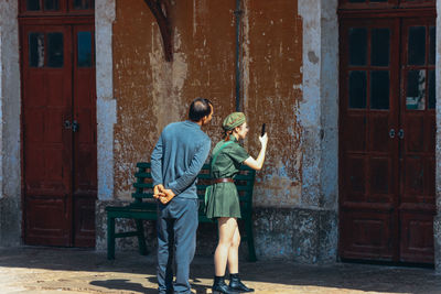 Rear view of man and woman standing against door of building