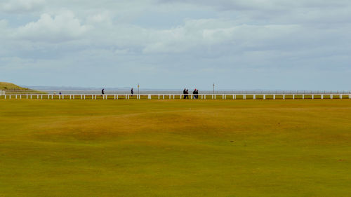 Group of people on grassland against the sky