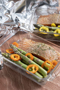 Raw red salmon with salt and spices with green asparagus and paprika in a dish