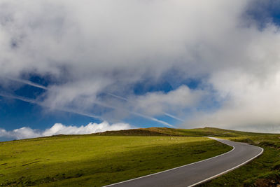 Scenic view of road amidst field against sky