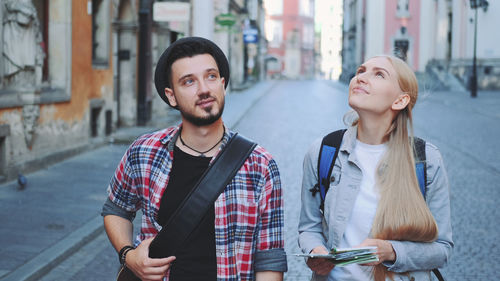 Man and woman holding map on footpath in city