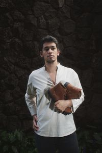 An image of a mixed race man carries brown high cut sneakers against stone walls