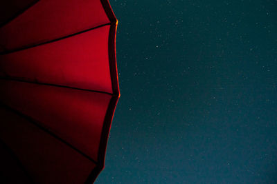 Low angle view of red parasol against sky at night
