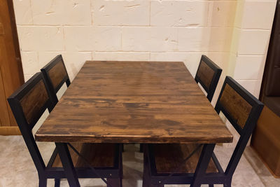 High angle view of empty chairs and table against wall