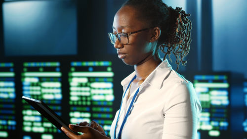 Side view of young woman using mobile phone in office