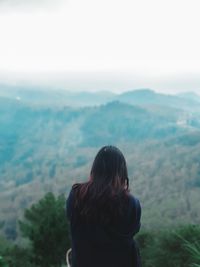 Rear view of woman looking at mountains against sky