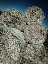 Close-up of hay bales on field against clear sky