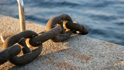 Close-up of rusty chain on rock at beach