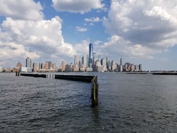 Sea by modern buildings against sky in city