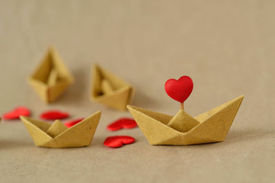Origami recycled paper boat with heart leading a group of boats - concept of love, and teamwork 
