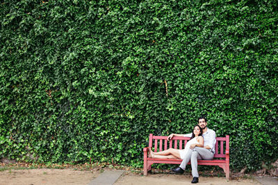 Couple relaxing while sitting on bench at park