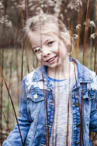 Portrait of smiling girl standing amidst sticks on field