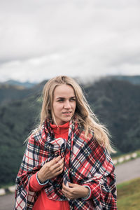 Woman looking away while standing against mountain